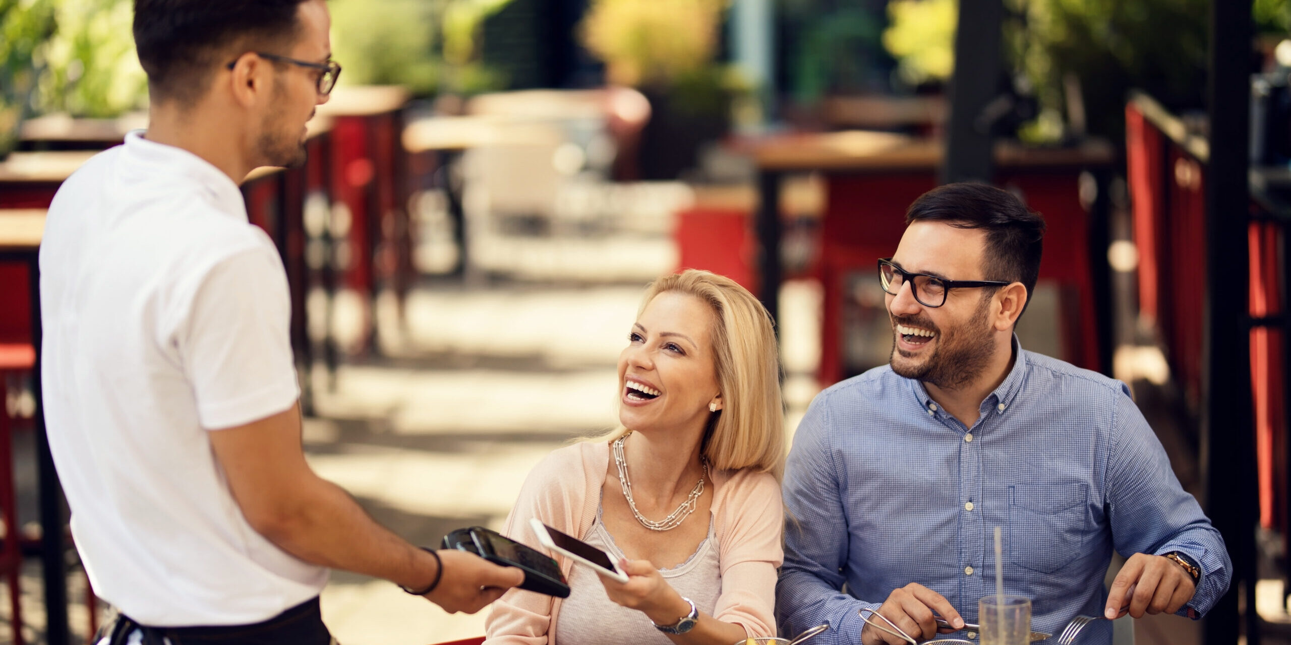 Waiter taking a smart phone payment from his guests in a restaurant.